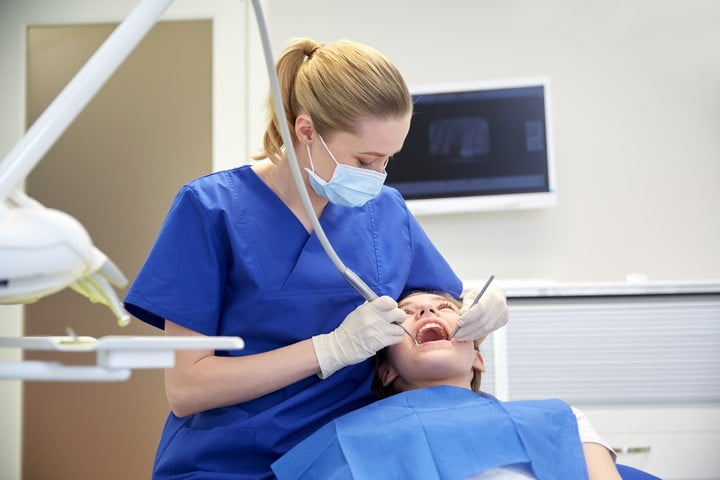 female dentist checking patient girl teeth